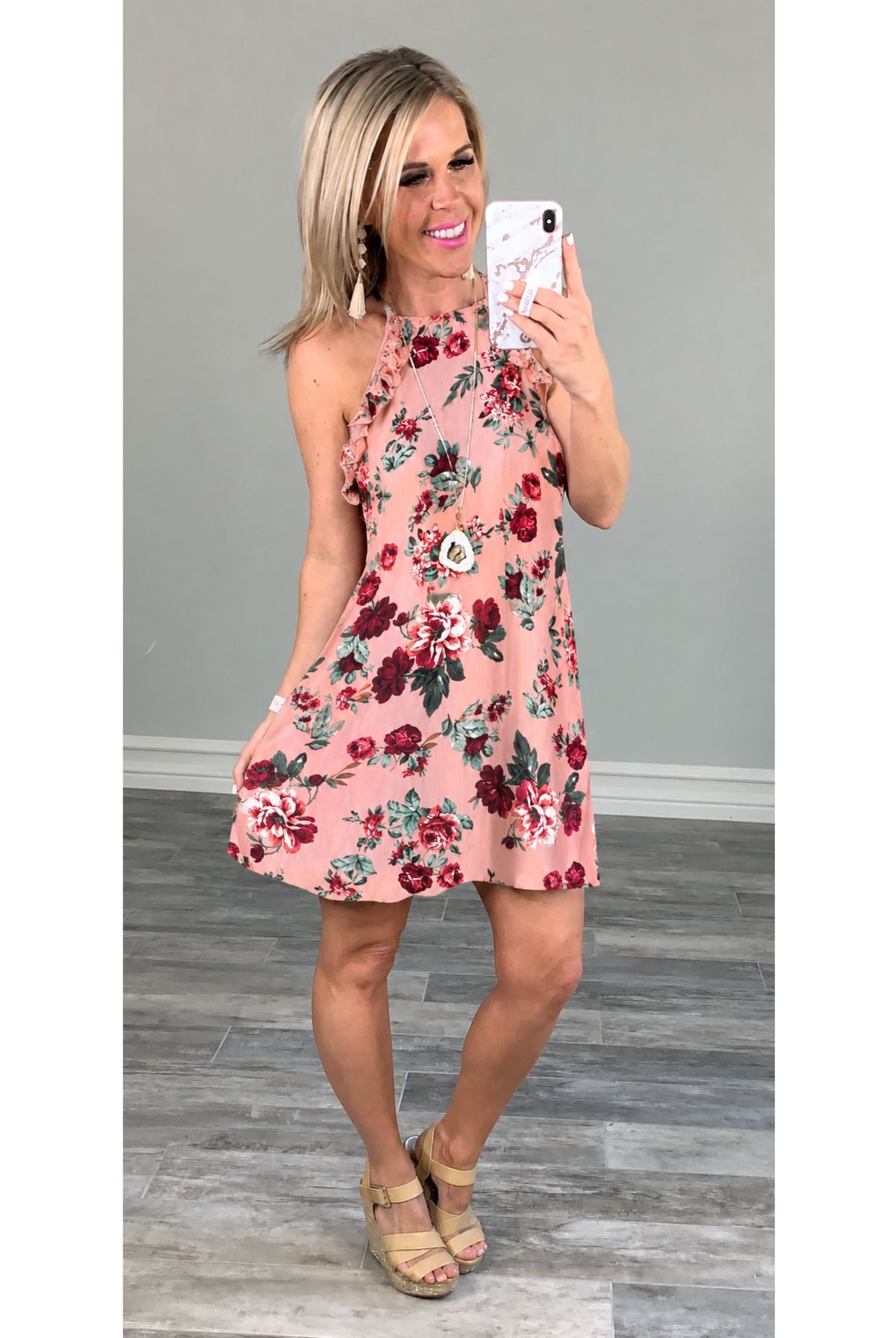Rose colored floral dress with ruffles at the sleeve open back, paired with wedges in a long necklace and earrings.