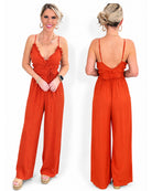 A woman modeling a bright rust-orange wide-leg jumpsuit.