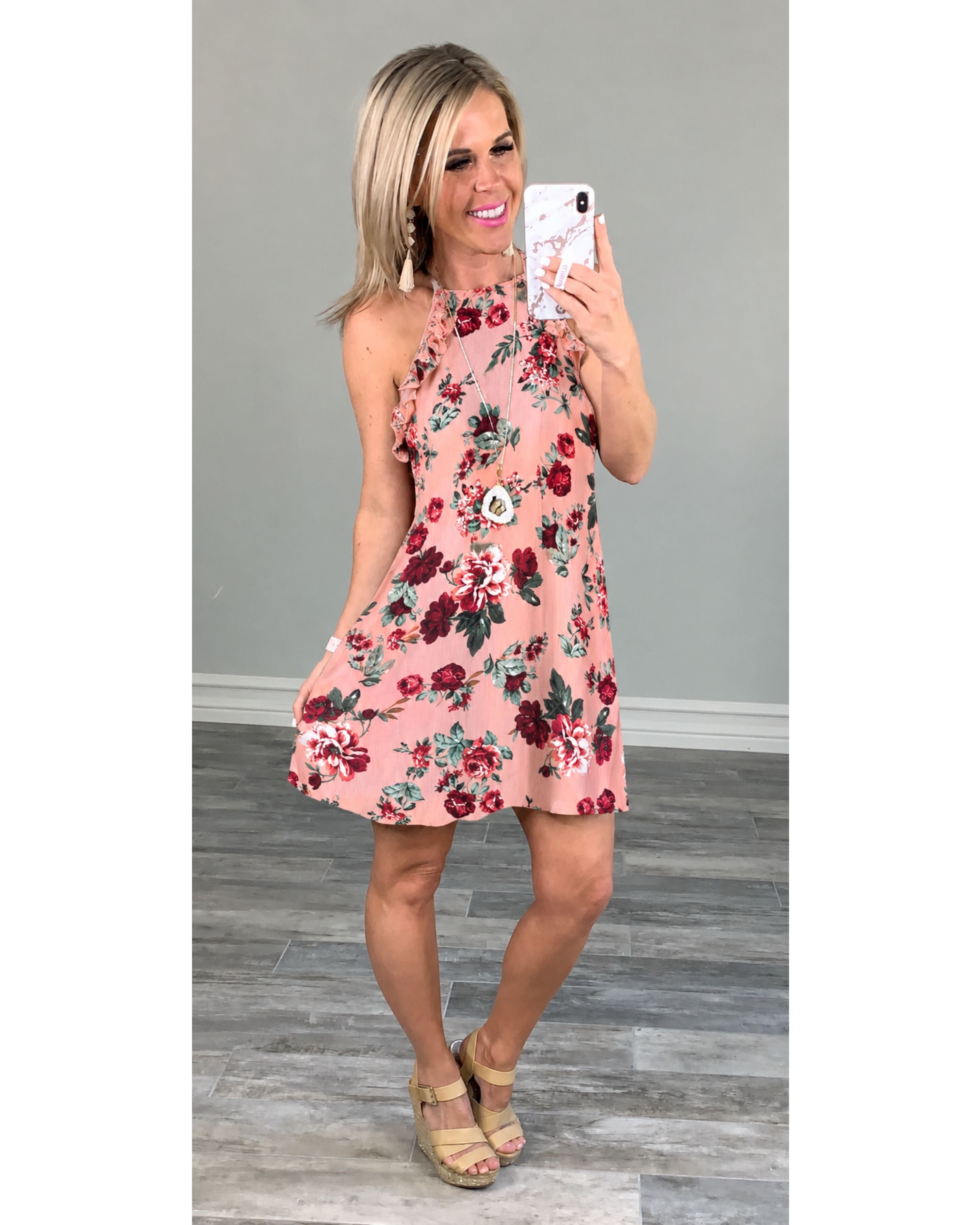 Rose colored floral dress with ruffles at the sleeve open back, paired with wedges in a long necklace and earrings.